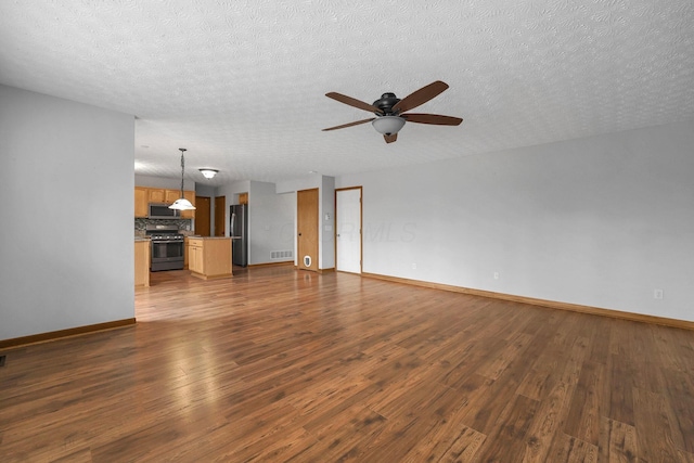 unfurnished living room featuring a textured ceiling, dark wood-type flooring, visible vents, baseboards, and a ceiling fan