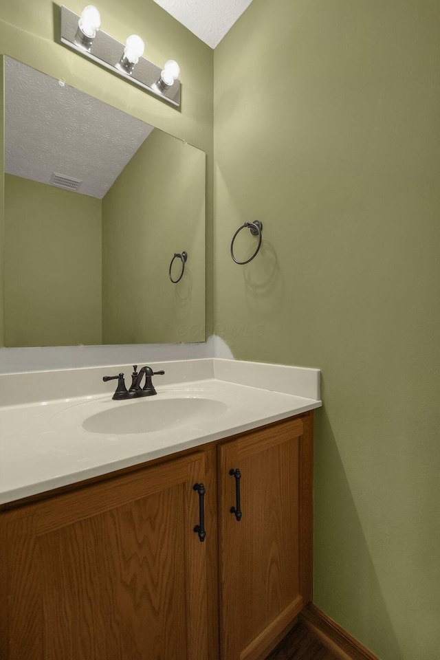 bathroom featuring baseboards, visible vents, a textured ceiling, and vanity