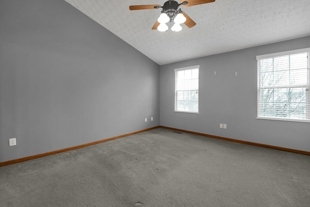 carpeted empty room featuring baseboards, vaulted ceiling, and a textured ceiling