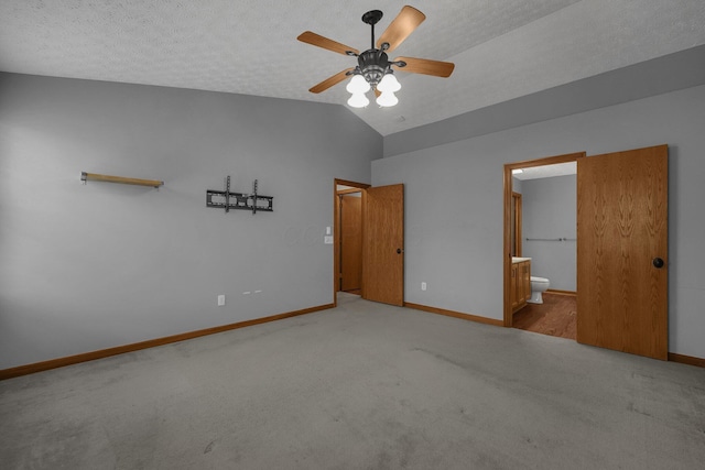 unfurnished bedroom featuring carpet floors, connected bathroom, vaulted ceiling, a textured ceiling, and baseboards