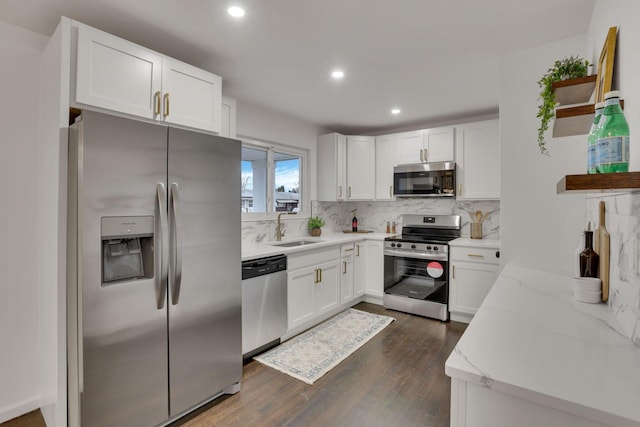 kitchen with sink, white cabinetry, backsplash, stainless steel appliances, and light stone counters