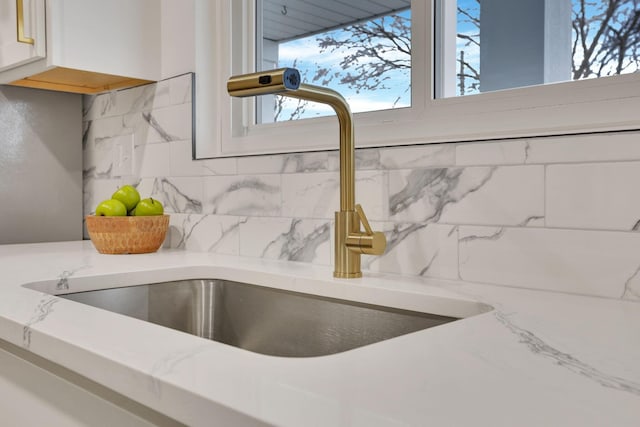 details featuring light stone countertops, sink, and decorative backsplash