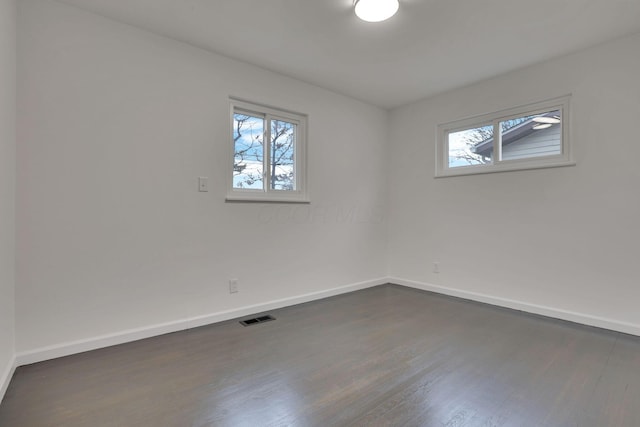 spare room with dark wood-type flooring and plenty of natural light