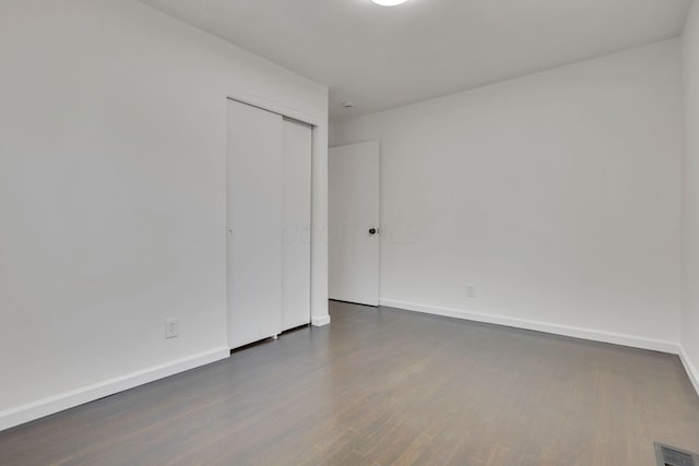 unfurnished bedroom with a closet and dark hardwood / wood-style floors