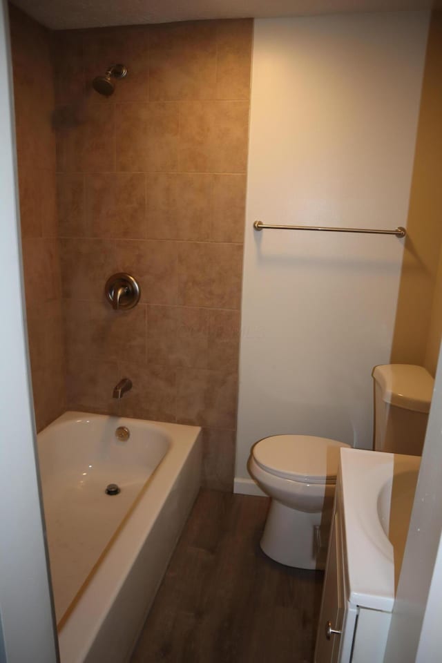 full bathroom featuring wood-type flooring, toilet, tiled shower / bath combo, and vanity