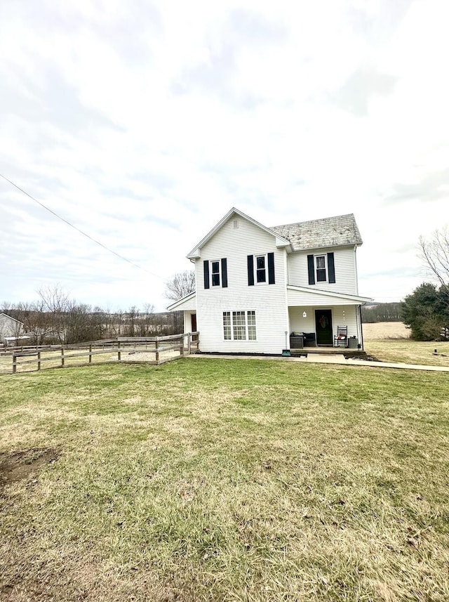 back of property with a rural view, central AC, and a lawn