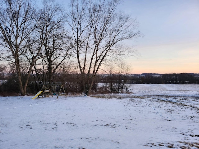 yard layered in snow featuring a playground