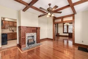 unfurnished living room with beamed ceiling, coffered ceiling, and light wood-type flooring