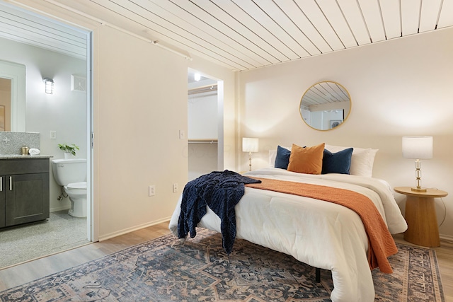 bedroom with wood ceiling, ensuite bath, and wood-type flooring