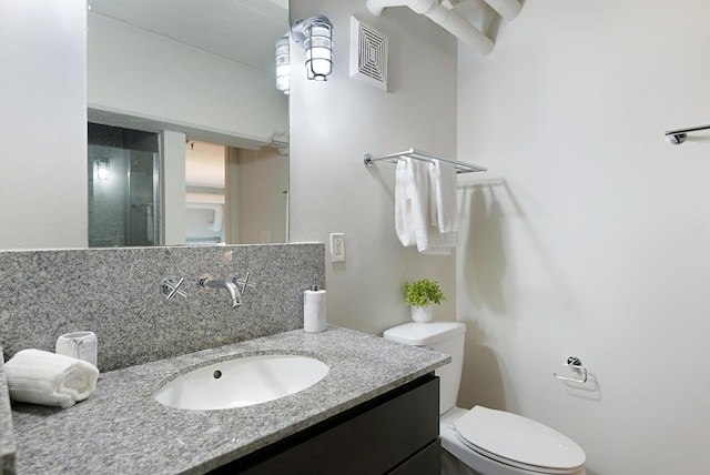 bathroom with vanity, backsplash, and toilet