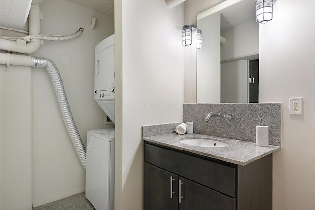 bathroom with stacked washer / dryer, vanity, and backsplash