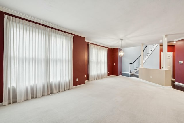 unfurnished living room with a notable chandelier, ornamental molding, and carpet flooring