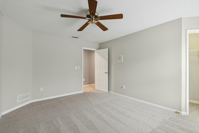 unfurnished bedroom featuring a spacious closet, light colored carpet, ceiling fan, and a closet