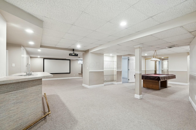 carpeted cinema room with pool table, sink, and a drop ceiling