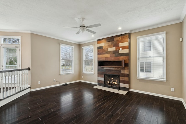 unfurnished living room with dark wood-type flooring, a large fireplace, ornamental molding, and ceiling fan