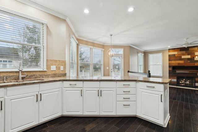 kitchen with white cabinetry, sink, decorative light fixtures, and kitchen peninsula