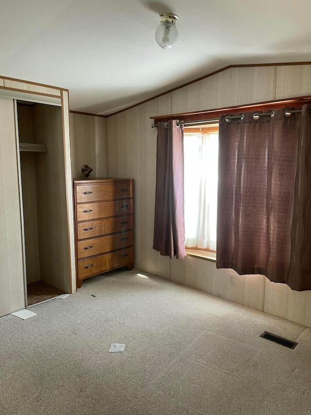 unfurnished bedroom with vaulted ceiling, light carpet, and a closet