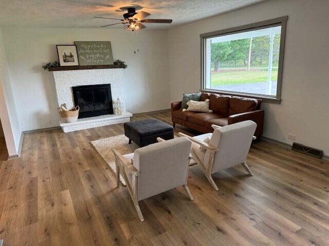 living room with ceiling fan, hardwood / wood-style floors, and a textured ceiling