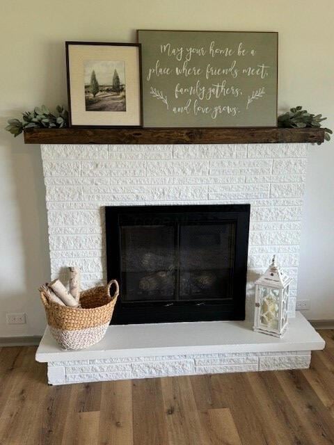 interior details featuring wood-type flooring and a tiled fireplace