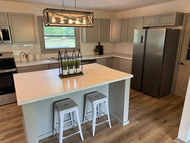 kitchen featuring hanging light fixtures, hardwood / wood-style flooring, a kitchen breakfast bar, and appliances with stainless steel finishes