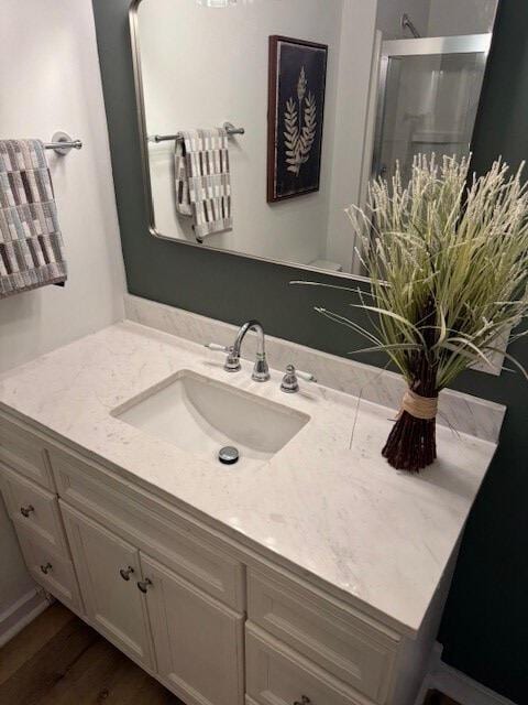 bathroom featuring vanity, a shower with shower door, and wood-type flooring