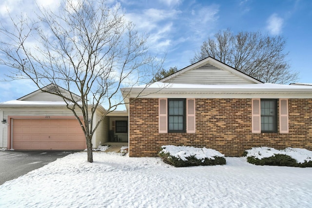 ranch-style home featuring a garage, driveway, and brick siding