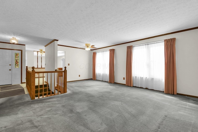 carpeted spare room with baseboards, ornamental molding, and a textured ceiling