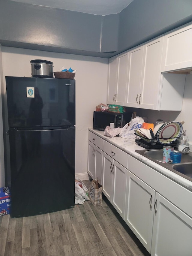 kitchen with dark wood-type flooring, sink, white cabinets, and black appliances