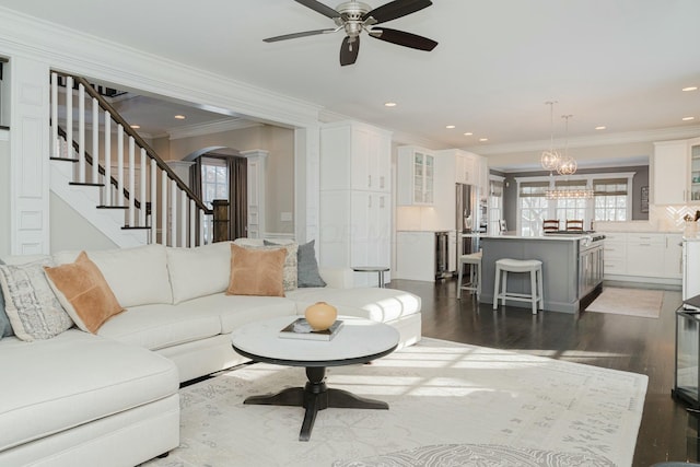 living room featuring ornamental molding, a healthy amount of sunlight, dark hardwood / wood-style floors, and decorative columns