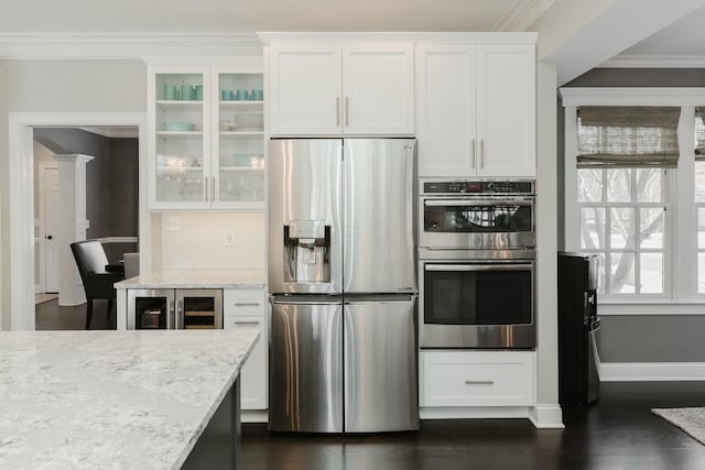 kitchen with white cabinetry, light stone counters, ornamental molding, and stainless steel appliances