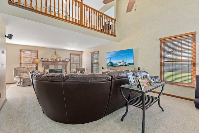 carpeted living room with a tiled fireplace, a towering ceiling, and ceiling fan