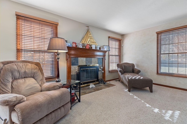 living room with a tiled fireplace, a healthy amount of sunlight, and carpet flooring