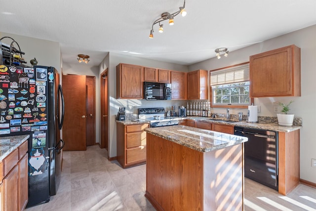 kitchen with sink, a center island, light stone counters, black appliances, and a textured ceiling