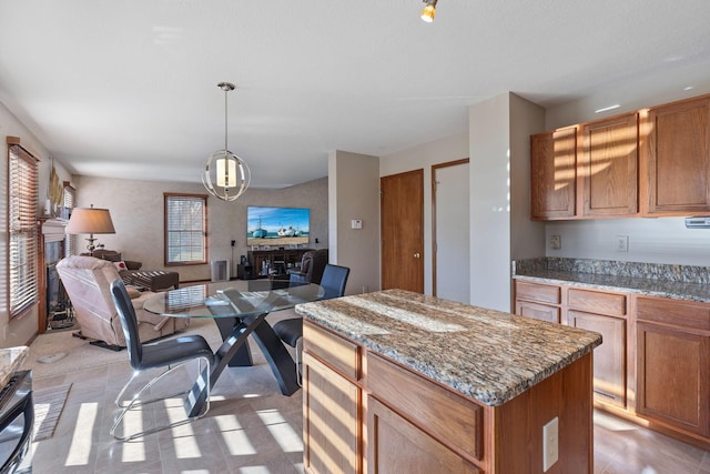 kitchen with decorative light fixtures, light stone countertops, and a kitchen island