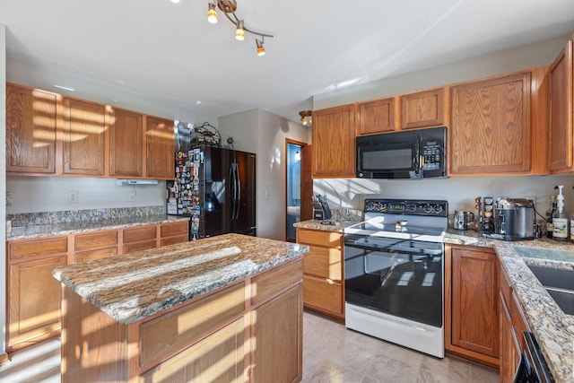 kitchen with light stone counters, black appliances, and a center island