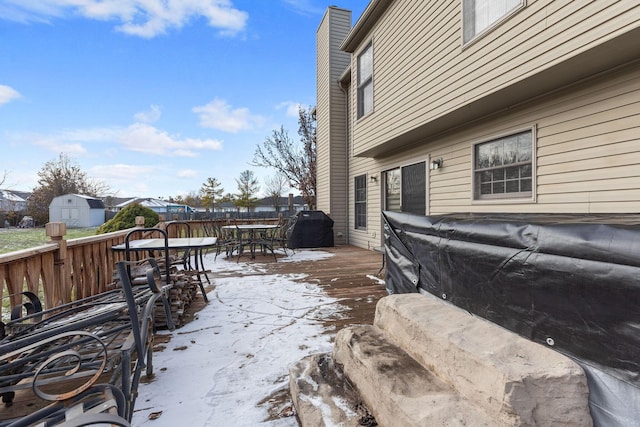 snow covered deck with grilling area and a storage unit