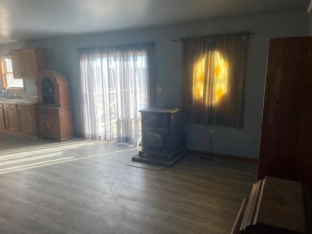 unfurnished living room with sink, a wood stove, and dark wood-type flooring