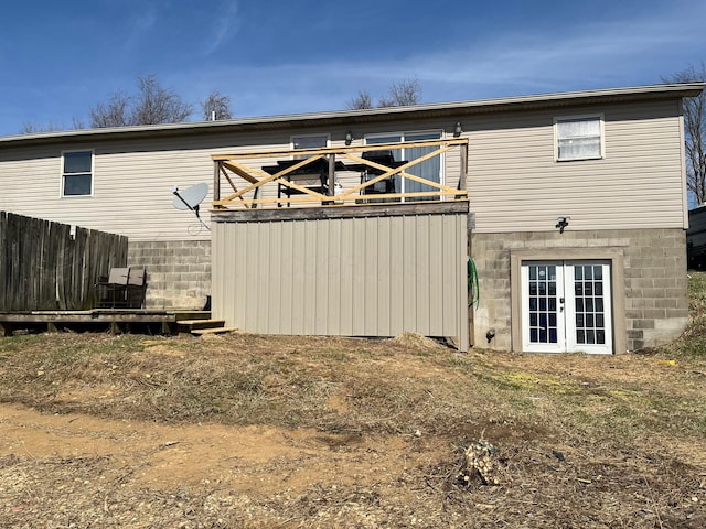 rear view of property with french doors, a deck, and fence