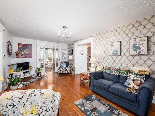 living room with hardwood / wood-style flooring, an inviting chandelier, and a textured ceiling