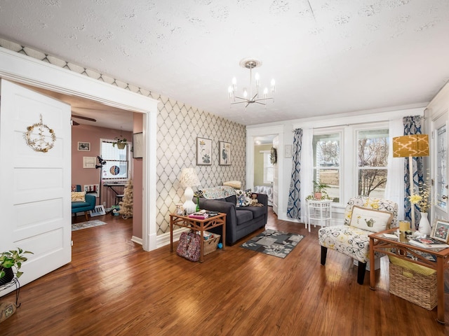 living room featuring dark wood-type flooring, a chandelier, and a textured ceiling