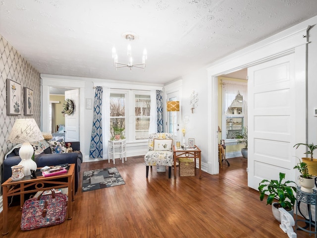 sitting room with dark wood-type flooring, a chandelier, and a textured ceiling