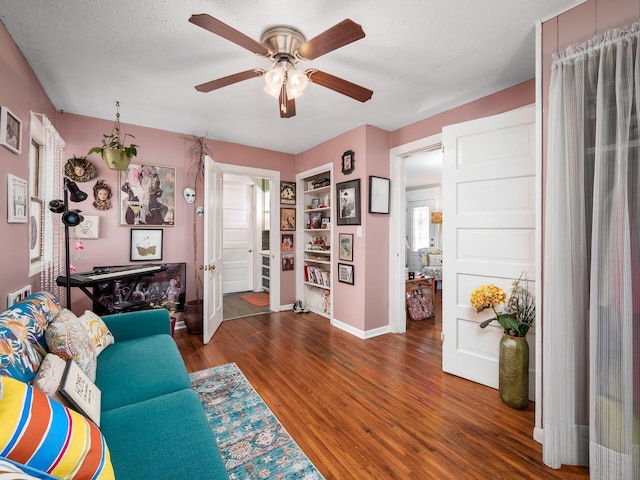 living room featuring dark wood-type flooring, a textured ceiling, and ceiling fan