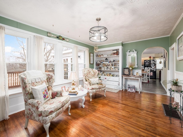 living area featuring dark hardwood / wood-style flooring, ornamental molding, and a textured ceiling