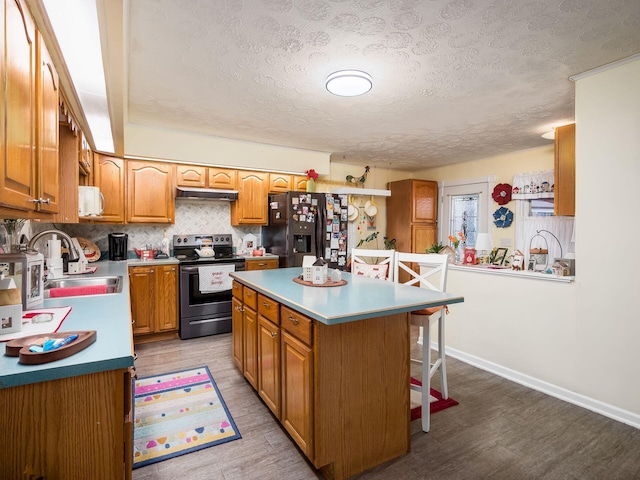 kitchen with a breakfast bar, sink, a center island, black refrigerator with ice dispenser, and stainless steel electric stove