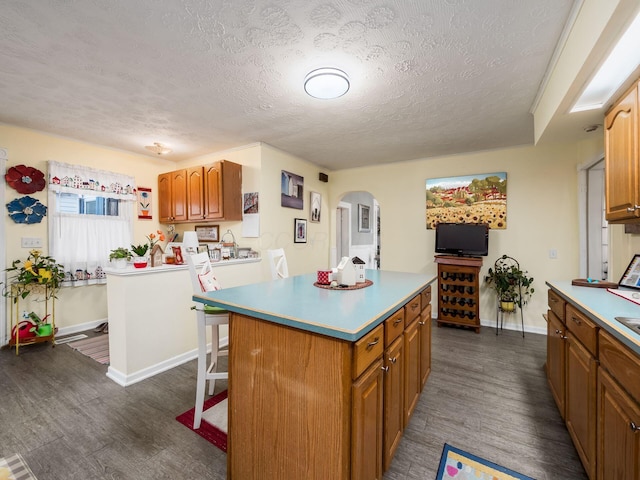 kitchen featuring a kitchen island, dark hardwood / wood-style floors, a kitchen bar, and a textured ceiling