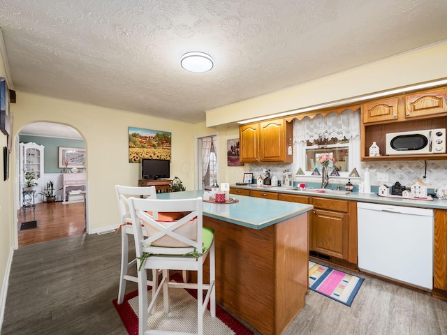 kitchen featuring a kitchen island, dark hardwood / wood-style floors, sink, decorative backsplash, and white dishwasher