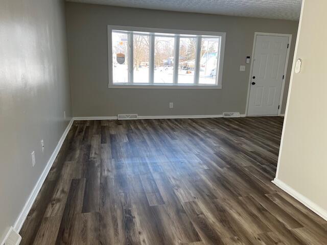 spare room featuring dark hardwood / wood-style flooring and a textured ceiling