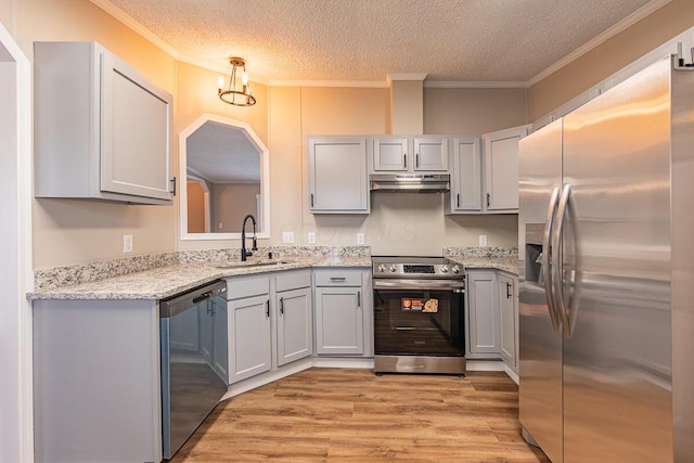 kitchen with sink, stainless steel appliances, ornamental molding, a textured ceiling, and light wood-type flooring