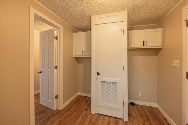 clothes washing area with hardwood / wood-style flooring, crown molding, and a textured ceiling