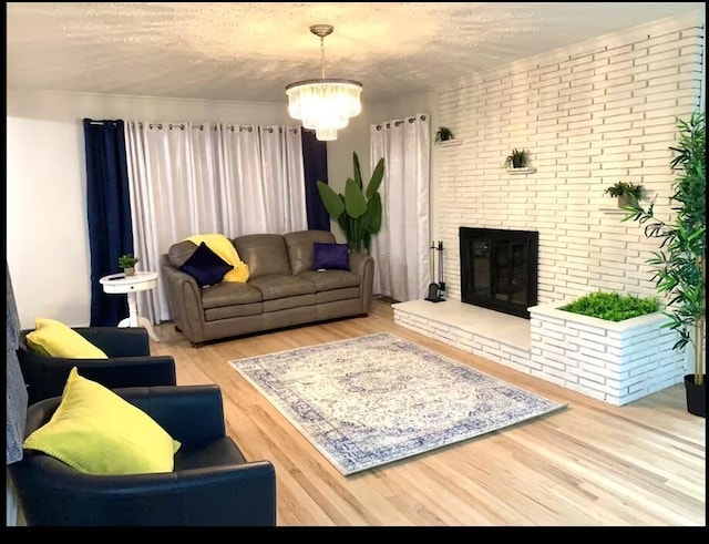 living room with hardwood / wood-style floors, a textured ceiling, brick wall, a brick fireplace, and a chandelier